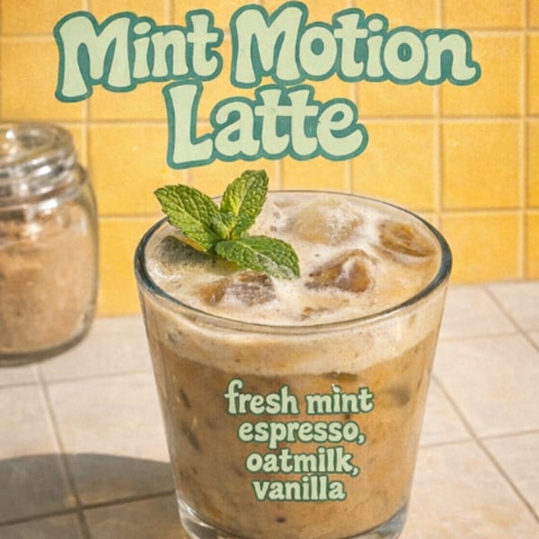 A Mint Motion Latte from Cafe Da Fonk, garnished with fresh mint, against a yellow tiled background.